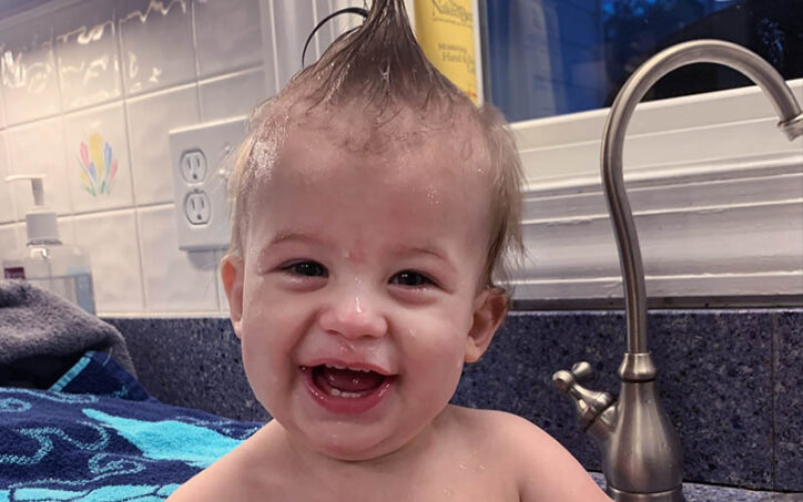 Un Myles souriant est assis dans un lavabo après un bain